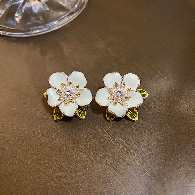 Pendientes de flores esmaltadas en color crema con circonitas brillantes y hojas