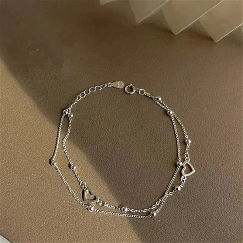 Elegante pulsera de doble cadena con corazones y cuentas finas