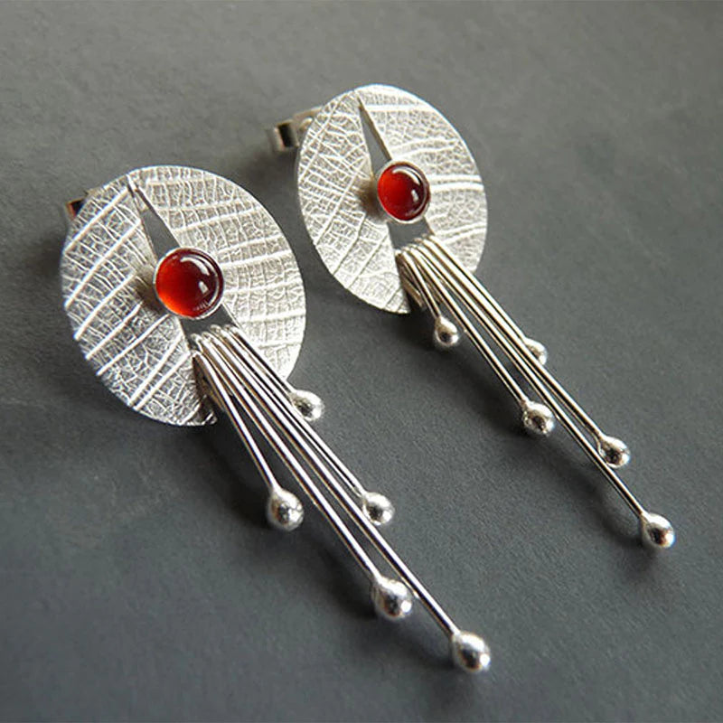 Pendientes artísticos con piedra de color rojo intenso y elementos colgantes modernos