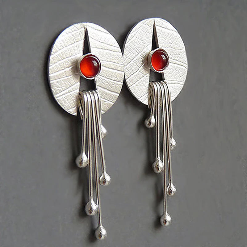 Pendientes artísticos con piedra de color rojo intenso y elementos colgantes modernos