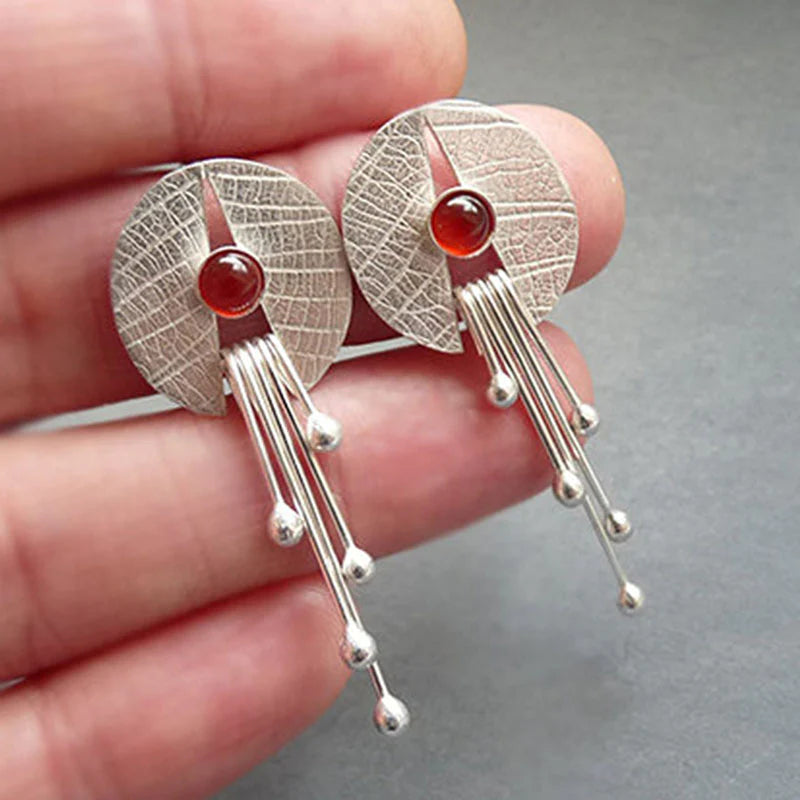 Pendientes artísticos con piedra de color rojo intenso y elementos colgantes modernos