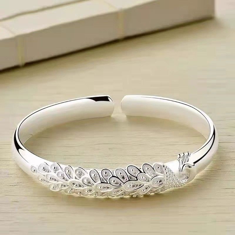 Elegante pulsera ajustable con un delicado diseño de plumas de pavo real