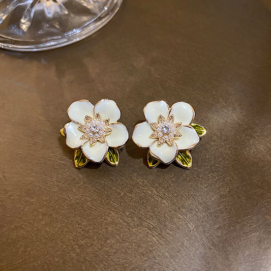 Pendientes de flores esmaltadas en color crema con circonitas brillantes y hojas
