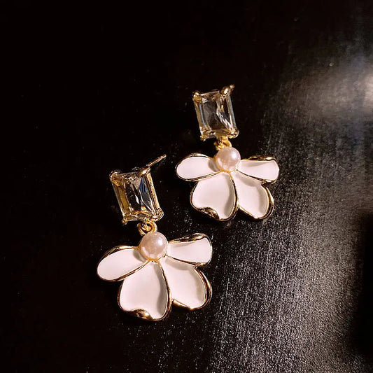 Pendientes elegantes de flores blancas con piedras brillantes y perlas