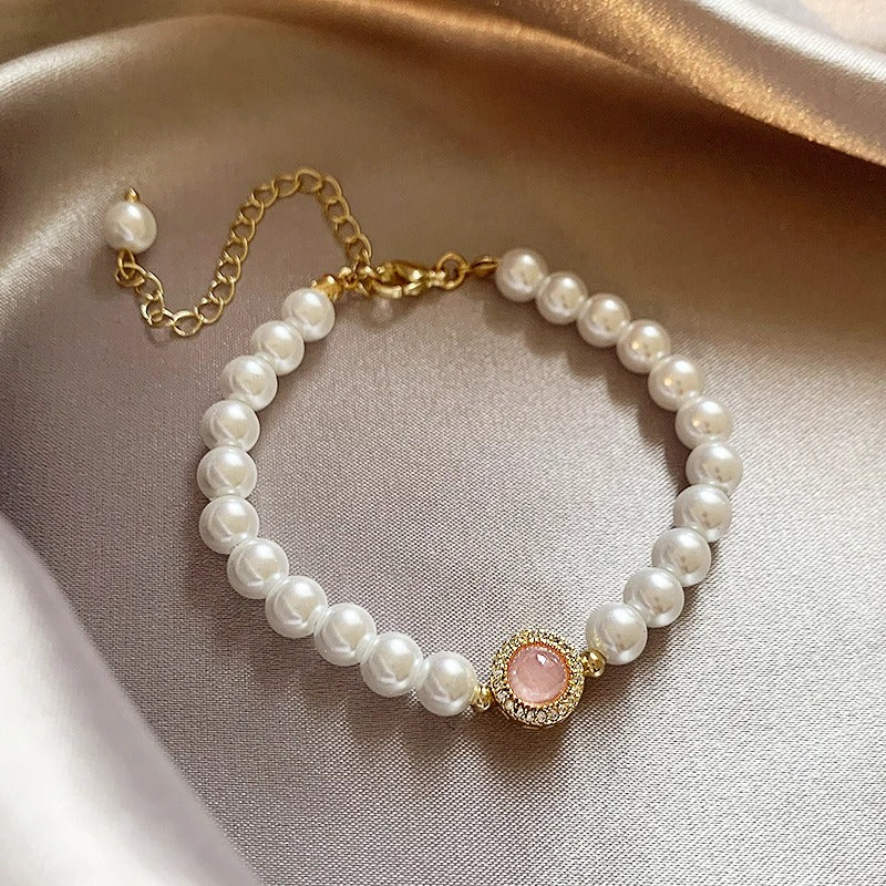 Elegante pulsera de perlas con detalles de piedras rosas y cadena extensible