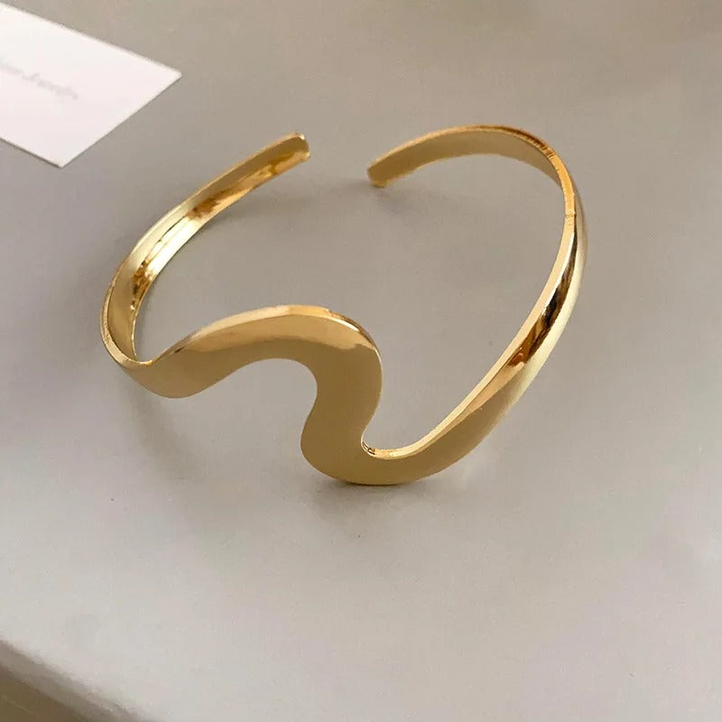 Elegante pulsera abierta con diseño ondulado y brillante